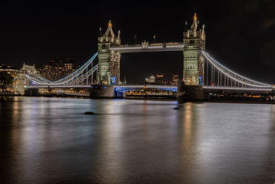Illuminated bridge over river at night