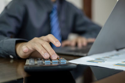 Midsection of businessman using laptop on table