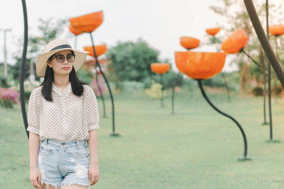 Young woman wearing hat standing against plants