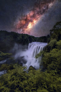 Scenic view of waterfall against sky in forest