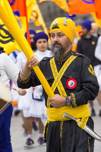 Full length of man holding yellow while standing outdoors