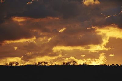 Silhouette landscape against dramatic sky during sunset