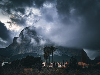 High angle view of townscape and mountain against cloudy stormy sky