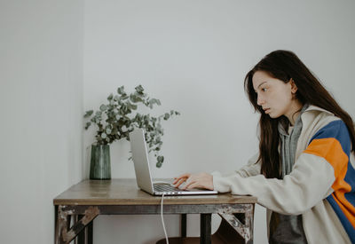 Young woman using laptop while sitting on table