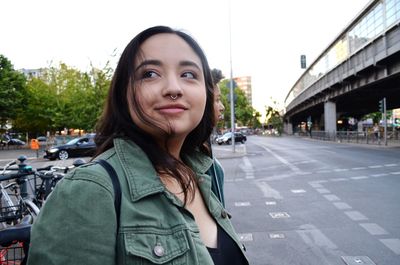 Portrait of young woman standing on road in city