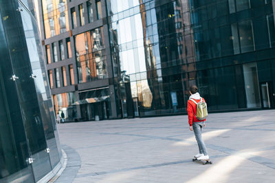 Young stylish man having fun with skateboard along the modern houses. urban and street photo. 