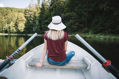 Rear view of woman sitting on boat in lake