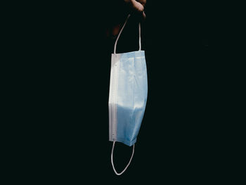 Close-up of hand holding umbrella against black background