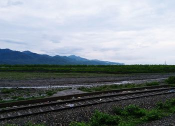 Railroad track amidst field against sky
