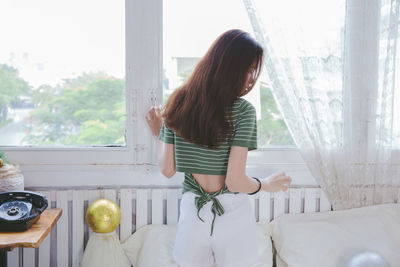 Woman looking through window at home