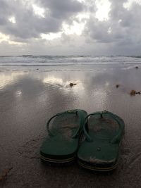 Shoes on beach against sky