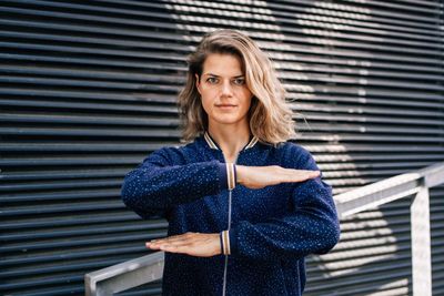 Portrait of young woman standing against blue wall