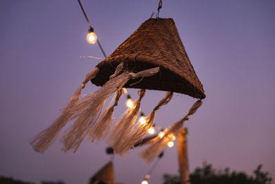 Low angle view of illuminated lighting equipment hanging against sky