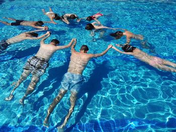 High angle view of people holding hands while swimming in pool