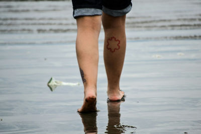 Low section of man standing on beach