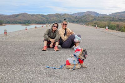 Portrait of friends with dog sitting on footpath