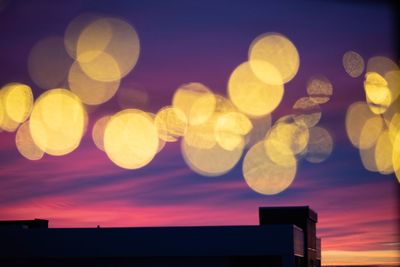 Low angle view of defocused lights against sky at night