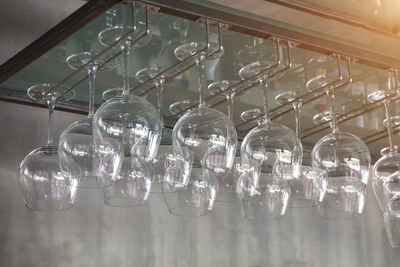 Low angle view of wineglasses hanging on rack in bar