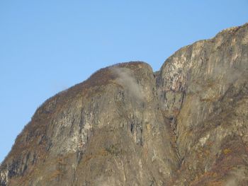 Low angle view of rock formation against clear blue sky