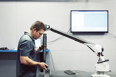 Side view of serious worker working on steel with equipment at industry