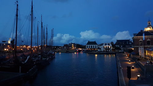 Sailboats moored at harbor in city against sky