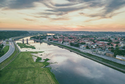 Aerial view of city by river against sky