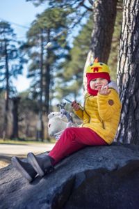 Boy sitting on tree trunk in forest