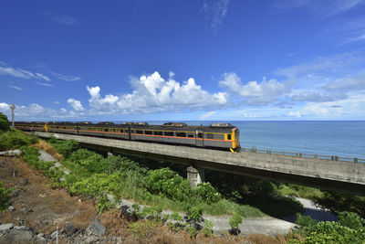 Train on bridge over sea against blue sky