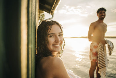 Portrait of happy woman looking over shoulder during vacation on sunset