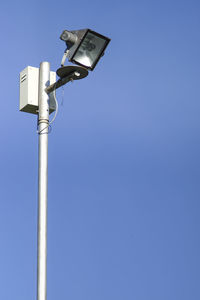 Low angle view of telephone pole against clear blue sky