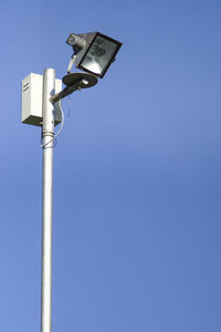 Low angle view of lighting equipment against clear blue sky