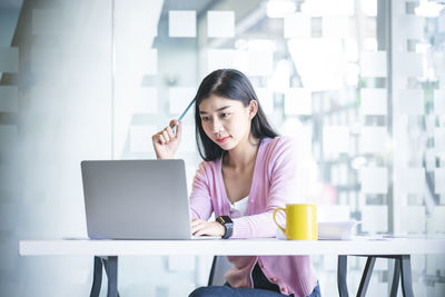 Young woman using phone on table