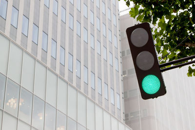 Low angle view of green light against modern office building in city