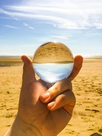 Cropped hand holding crystal ball art beach