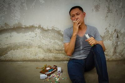 Mature man sitting by narcotics against wall