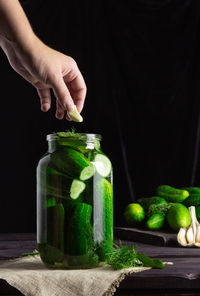 Midsection of man holding fruit in jar on table