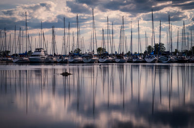 Boats moored at harbor against cloudy sky at dusk