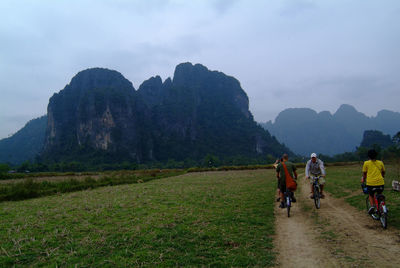 Rear view of people riding bicycle on mountain against sky