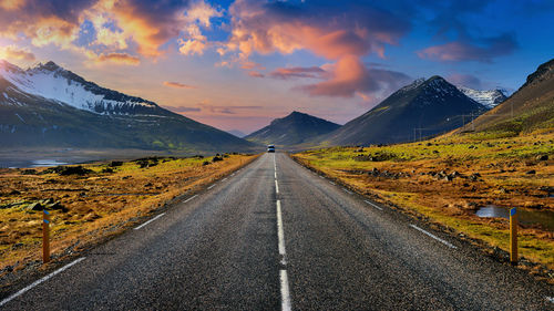 Road amidst snowcapped mountains against sky