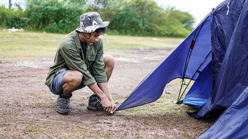 Young man setting tent at campsite