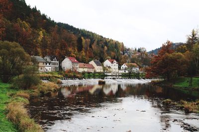 Houses at lakeshore by tree mountain during autumn