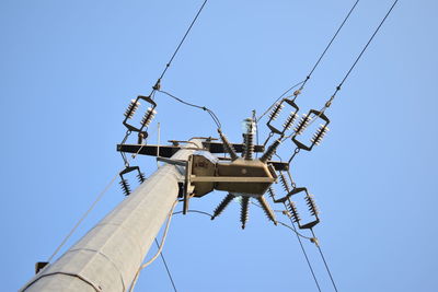 Low angle view of telephone pole against clear blue sky