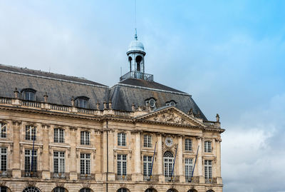 Low angle view of place de la bourse against cloudy sky