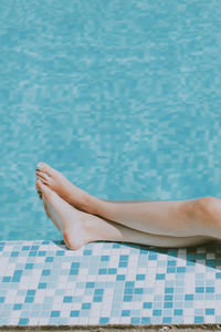 Low section of woman lying on swimming pool