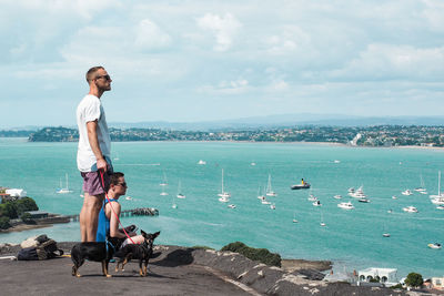 Men with dog on shore against sky