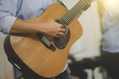 Midsection of man playing guitar