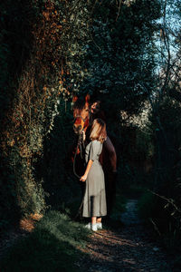 Woman standing on footpath amidst plants in forest