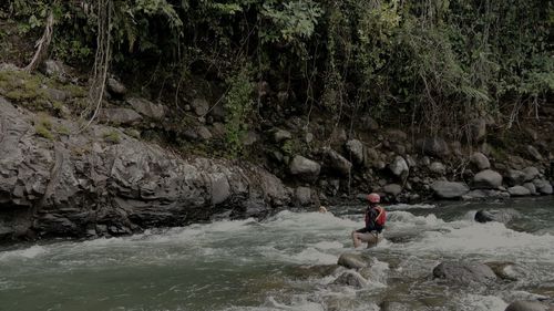 Man surfing on rock by river