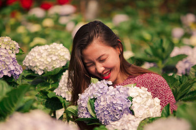 Close-up of smiling woman with flower petals on plant