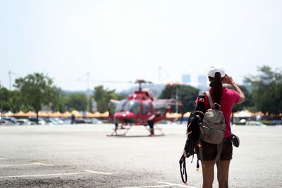 Rear view of woman carrying backpack while standing on airport runway